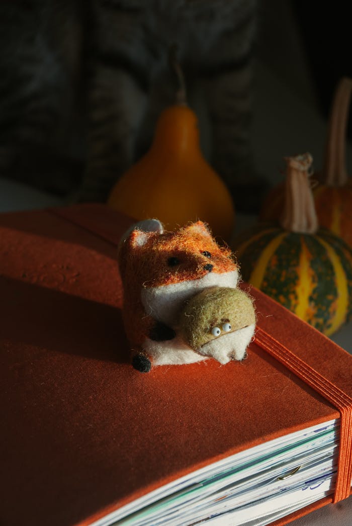 Felt fox toy on a book with autumn decor, embodying cozy fall vibes.